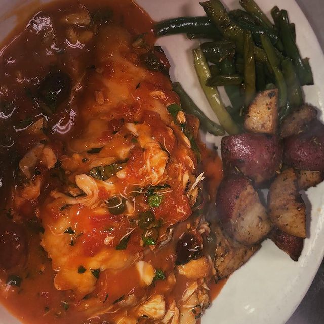 A white plate with chicken, potatoes and green beans.